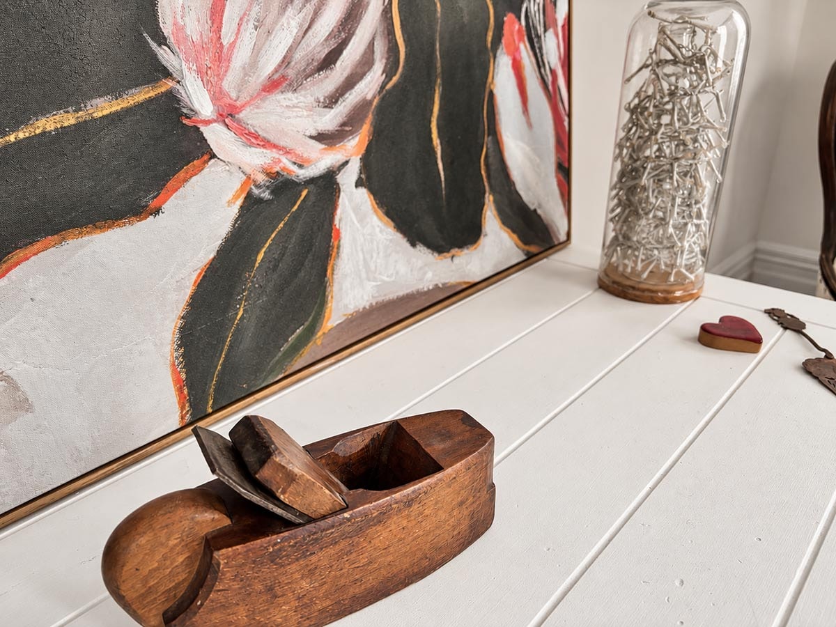Wooden hand plane tool displayed alongside abstract artwork