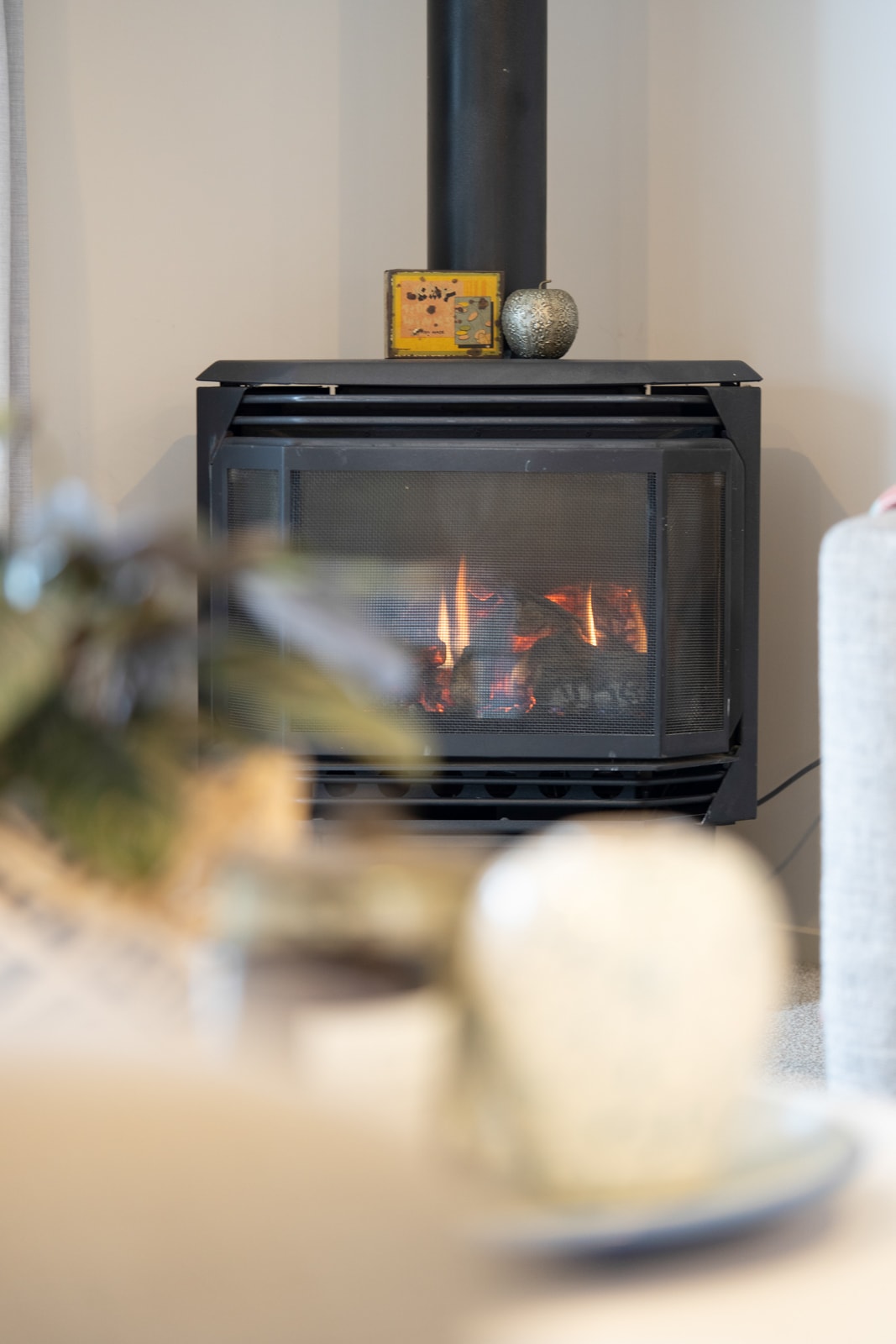 Black cast-iron fireplace with lit flames in a staged interior