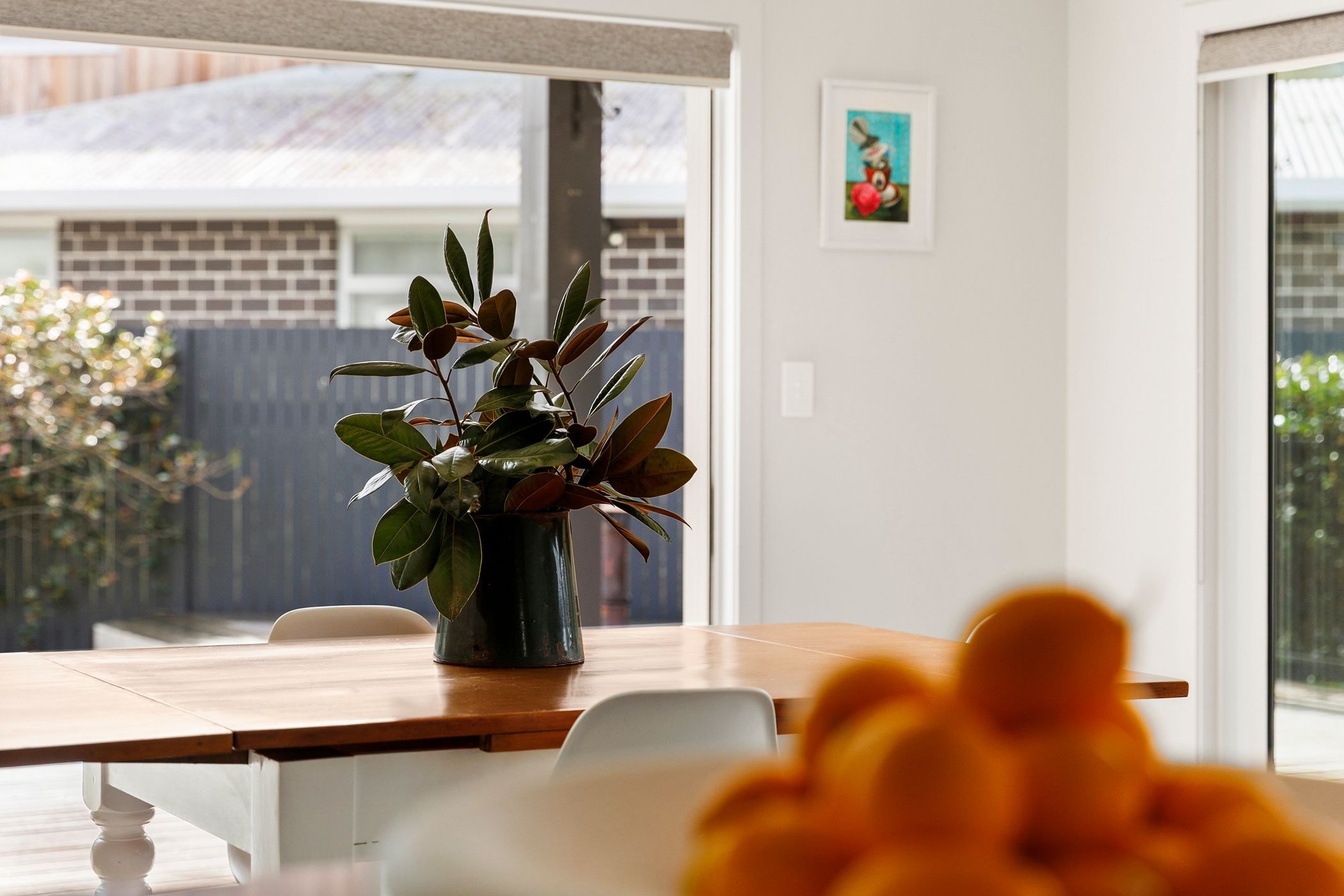 Dining table with a potted plant beside a window